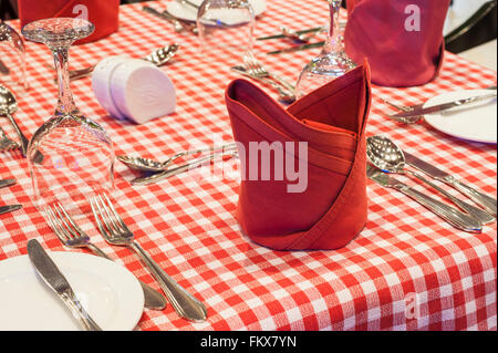 Primo piano dettaglio di una tabella sul rosso controllato tabella panno con posate in argento Foto Stock