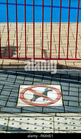 I cani non firmare sul pavimento lastricato di un parco giochi per bambini area su un nuovo costruire alloggi estate. Bicester, Oxfordshire Inghilterra Foto Stock