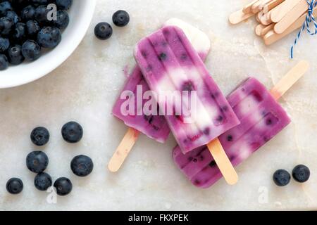 Mirtillo vaniglia popsicles in un cluster con frutti di bosco freschi su un marmo bianco sullo sfondo Foto Stock