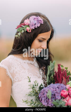 Ritratto di bella sposa con bouquet viola in mani vicino fino Foto Stock