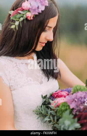 Bella bruna sposa con bouquet in mano vicino fino Foto Stock