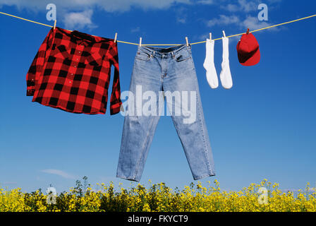 Panni stesi su una linea di abbigliamento al di sopra di un giallo fiore canola field Foto Stock