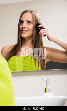 Giovane donna pettinare i capelli Foto Stock