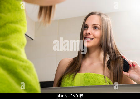 Giovane donna pettinare i capelli Foto Stock