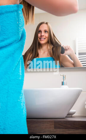 Giovane donna pettinare i capelli Foto Stock