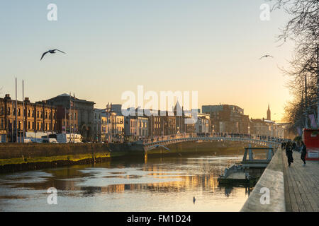 Dublino Irlanda al tramonto: turisti in piedi sul Ha'penny Bridge e guardare il tramonto sopra il fiume Liffey Foto Stock