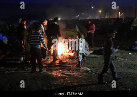 Idomeni, Grecia, 10 marzo 2016. I rifugiati ottenere caldo a un falò al confine Greek-Macedonian vicino al villaggio greco di Idomeni, dove migliaia di rifugiati e migranti sono intrappolati dal confine dei Balcani blocco. . Credito: Orhan Tsolak / Alamy Live News Foto Stock