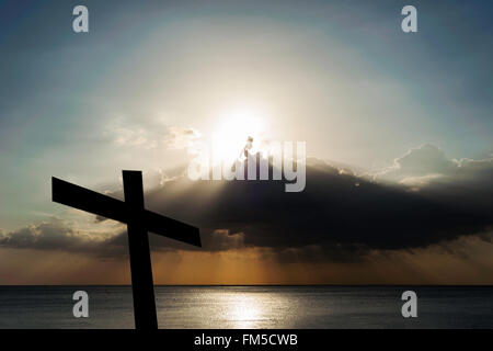 Silhouette a croce con raggi solari del bruciatore a fiamma viva e il cielo e il mare in oltre la luce del sole Foto Stock