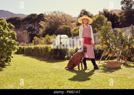 Senior donna nel suo cortile con un fedele cane Foto Stock