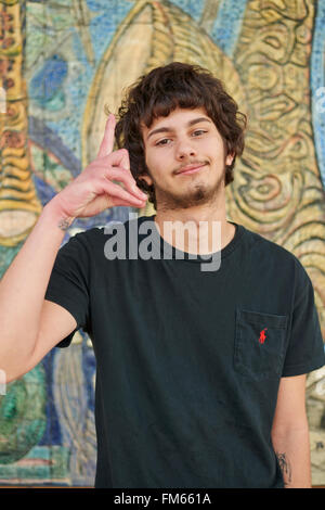 Giovane uomo in posa e la realizzazione di una mostra delle mani, Miami, Florida Foto Stock