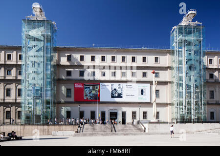 Una vista esterna di un edificio e l'entrata principale facciata per il Museo Nacional Centro de Arte Reina Sofia, Museo di Madrid con persone circa di fresatura esterna tra le due torri di vetrate con gli ascensori e le scale. Foto Stock