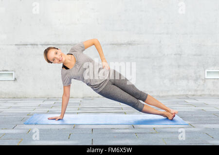 Donna fare yoga nella posizione del cobra pone sul tappeto Foto Stock