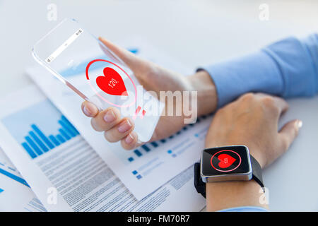 Mani con icona a forma di cuore sulla smartphone e smartwatch Foto Stock