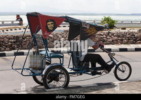 La vita quotidiana a Cuba - Locale uomo Bicicletta Equitazione taxi lungo il lungomare di Cienfuegos, Cuba nel Marzo Foto Stock
