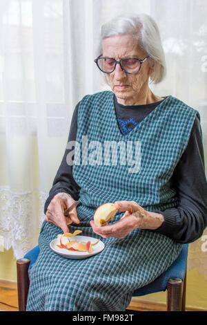 Novanta anni nonna la tranciatura e la sfogliatura di un Apple in ambienti interni Foto Stock