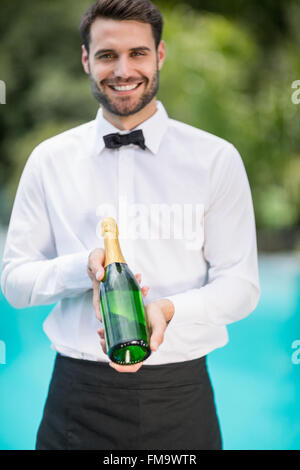 Ritratto di cameriere sorridente tenendo la bottiglia di champagne Foto Stock