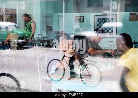 Cuba, Villa Clara, Caibarien, riflessi della strada dove moto e macchine che passano sul vetro di un club di scacchi Foto Stock