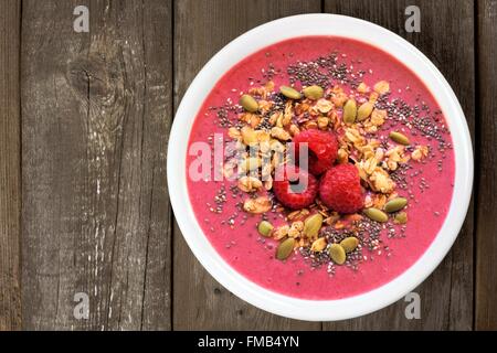 Ciotola frullato con lamponi, granola e chia semi su un legno rustico sfondo, vista aerea Foto Stock