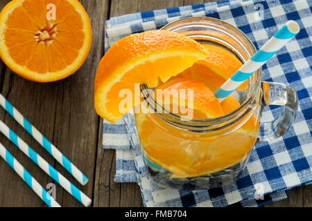 Detox acqua con arance e mirtilli in un mason jar con la paglia. Vista verso il basso in legno con panno a scacchi. Foto Stock