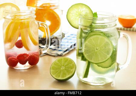 Detox acqua con vari tipi di frutta in vasetti di vetro su un tavolo Foto Stock