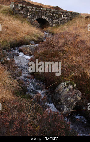 Flusso che scorre sotto il vecchio ponte di pietra. Rannoch Moor, nr Glencoe, Highlands Scozzesi. L'autunno. Foto Stock