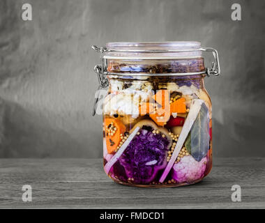 Jar assortiti di messi in salamoia lacto-fermentati sottaceti su un tavolo di legno con dissaturato sfondo. Foto Stock