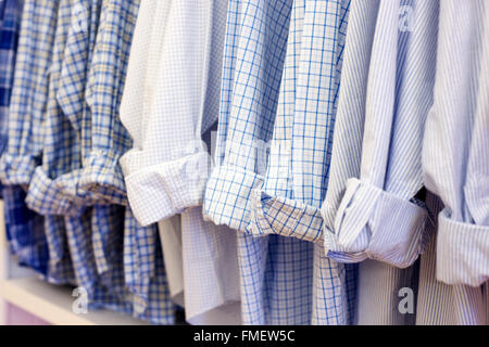 Uomini di colore blu e bianco, plaid e cotone a strisce di camicie, manicotti ammanettato, appeso in una fila. Foto Stock