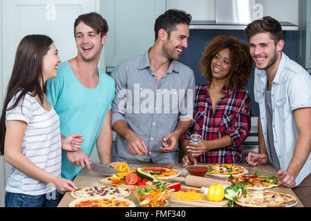 Allegro multi-etnico amici preparare la pizza a casa Foto Stock