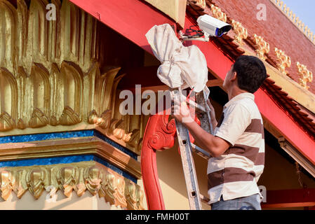 Uomo di installare una telecamera di sicurezza sul tempio, Vientiane Laos Foto Stock