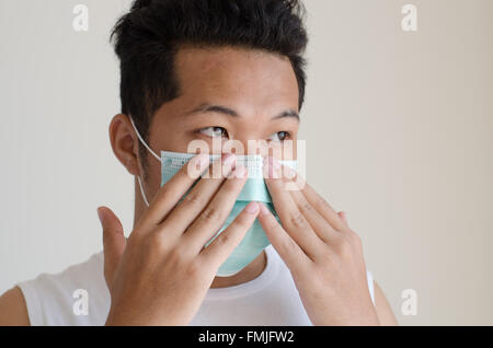 Uomo asiatico che indossa una maschera per il viso Foto Stock