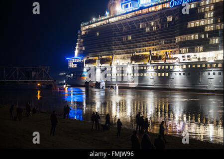 La più recente nave da crociera del cantiere Meyer chiamato 'ovazione dei mari' essendo trasferita attraverso la stretta del fiume Ems per il Mare del Nord, Papenburg, Germania, 11 marzo 2016. A circa 348 metri di lunghezza della nave passeggeri verrà più tardi in darsena Duthc Eemshaven e poi continuare il suo viaggio a Bremerhaven al fine di essere preparati per il trasferimento a US Shipping Company "Ryal Caribbean International'. Foto: INGO WAGNER/dpa Foto Stock