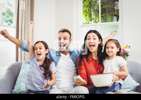 Famiglia tifo mentre si guarda il TV a casa Foto Stock