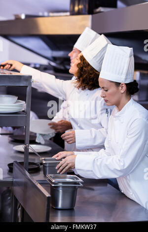 Due chef lavorano a stazione di ordine in cucina Foto Stock