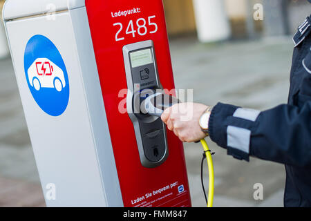 Amburgo, Germania. 09Mar, 2016. Un funzionario di polizia si inserisce una spina in un polo di ricarica per auto elettriche ad Amburgo, Germania, 09 marzo 2016. La città di Amburgo ha istituito un nuovo polo di ricarica incluse nuove indicazioni per il parcheggio gratuito e la ricarica delle auto elettriche su Schoenhausener Allee (lit. Schoenhausen Avenue). Foto: LUKAS SCHULZE/dpa/Alamy Live News Foto Stock