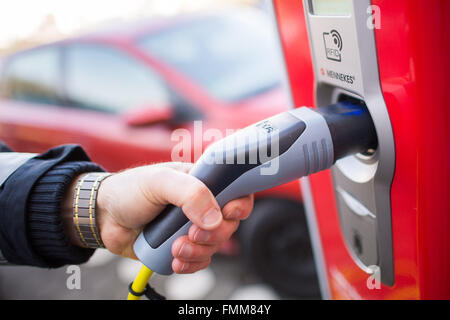 Amburgo, Germania. 09Mar, 2016. Un funzionario di polizia si inserisce una spina in un polo di ricarica per auto elettriche ad Amburgo, Germania, 09 marzo 2016. La città di Amburgo ha istituito un nuovo polo di ricarica incluse nuove indicazioni per il parcheggio gratuito e la ricarica delle auto elettriche su Schoenhausener Allee (lit. Schoenhausen Avenue). Foto: LUKAS SCHULZE/dpa/Alamy Live News Foto Stock