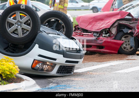 Rollover veicolo incidente ad incrocio occupato con il personale dei servizi di emergenza sulla scena Foto Stock