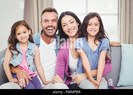 Ritratto di genitori seduto con le figlie sul divano Foto Stock