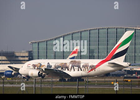 Emirates Airlines Airbus A380-800 A6-EEI rullaggio passato il Terminal 5 di Londra Heathrow Airport, Regno Unito Foto Stock