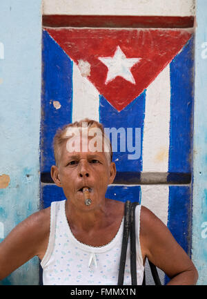 Donna cubana di fumare il sigaro dalla parete spiovente con dipinti bandiera di Cuba, La Habana Vieja, Havana, Cuba Foto Stock