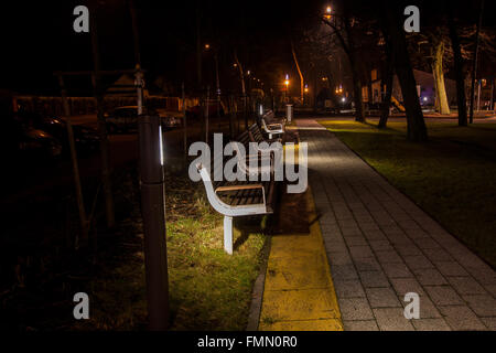 Una notte foto di panchine nel parco illuminate solo lampade stradali Foto Stock