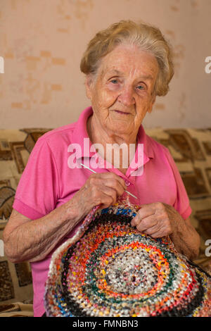 Una vecchia donna si siede la tessitura di un tappeto. Foto Stock