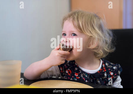 Bimba bionda di mordere in un panino con cioccolata spalmabile, Germania Foto Stock