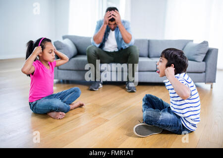 Infastiditi padre seduto sul divano mentre i bambini combattimenti Foto Stock