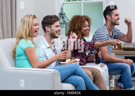 Allegro multi-etnico amici godendo di partite di calcio a casa Foto Stock