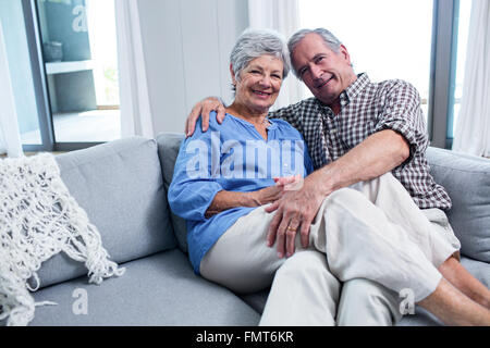 Ritratto di coppia senior che abbraccia ogni altra sul divano Foto Stock
