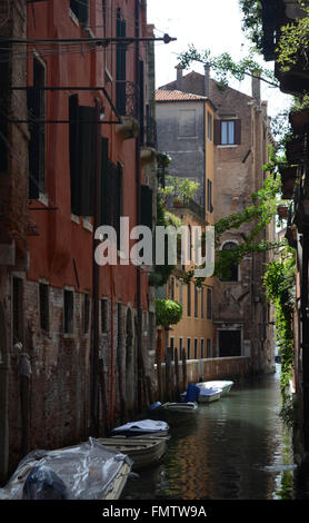 Un tranquillo canale di Venezia, che affianca gli edifici di vecchia costruzione.Alcune piccole barche sono ormeggiate lungo il canale. Foto Stock