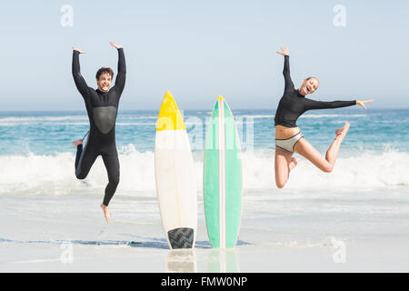 Eccitato giovane jumping accanto a tavole da surf Foto Stock