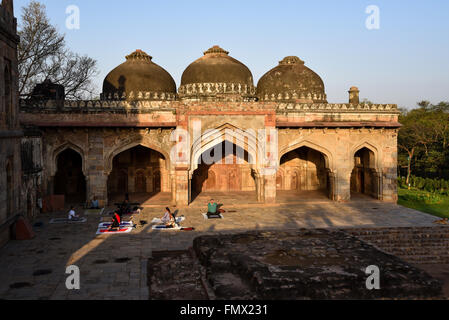 Un gruppo di persone di eseguire lo yoga la mattina presto nella parte anteriore della moschea vicino a bada Gumbad nel giardino Lodhi, New Delhi, India Foto Stock