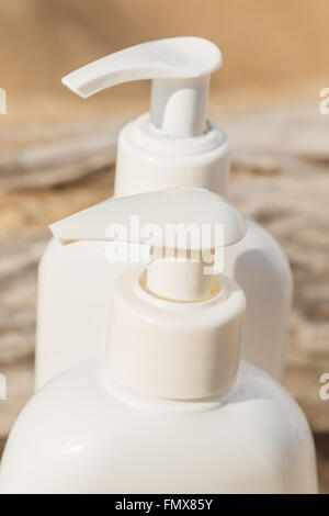 Bottiglie di bianco di cosmetici sulla spiaggia Foto Stock