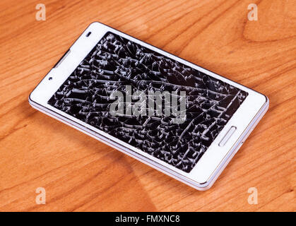 Rotto il telefono cellulare sulla massa di legno Foto Stock